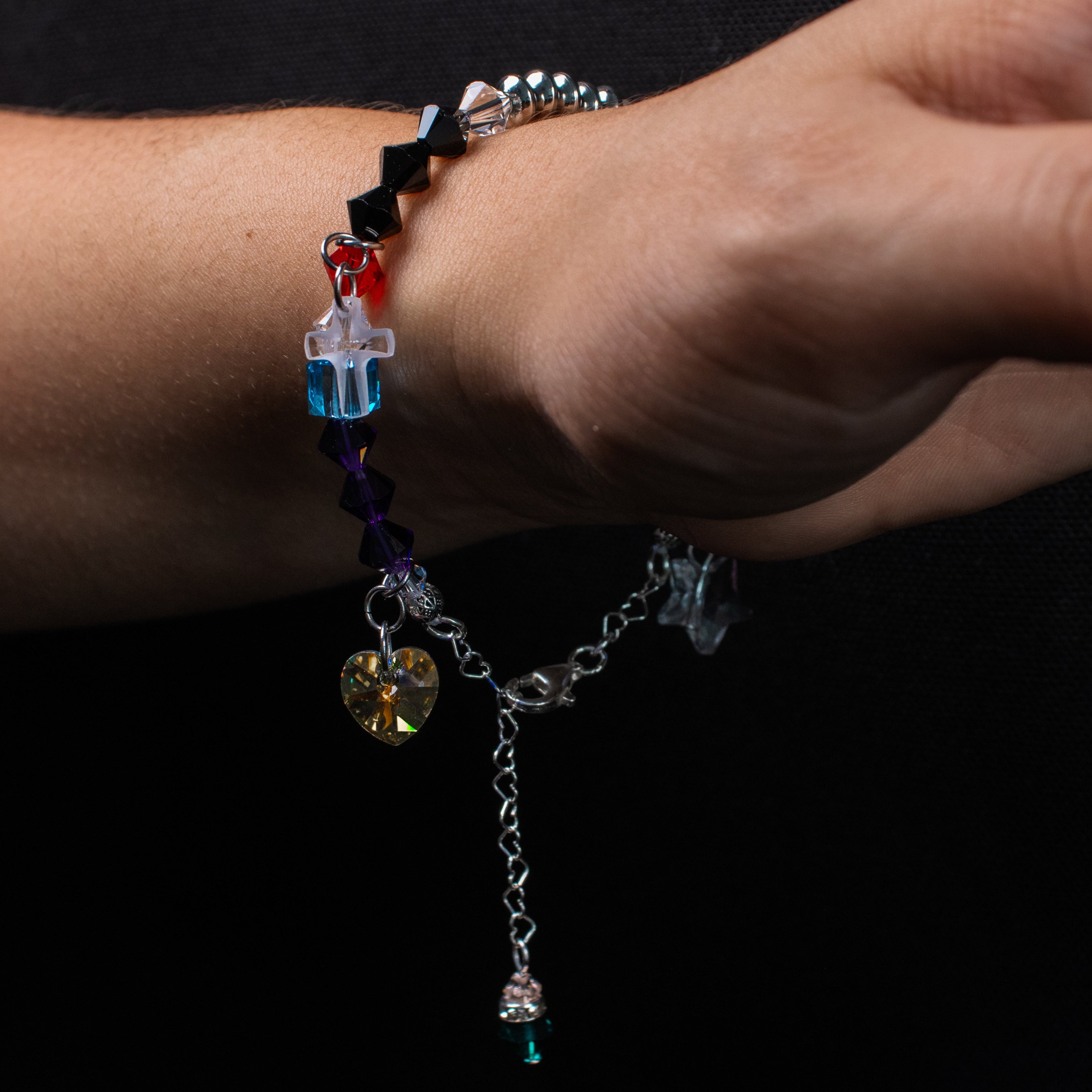 Close-up of a hand wearing a colorful beaded bracelet on a black background